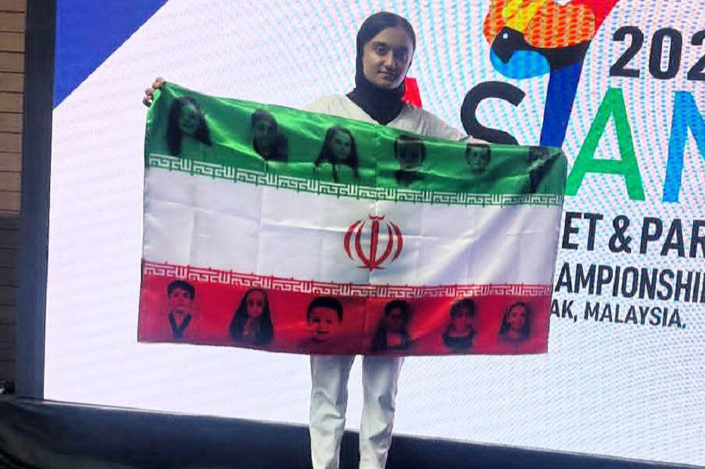 زهرا رحیمی، با پرچم یادبود شهدای کودک بر سکوی آسیا